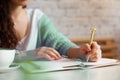 Well groomed woman hand holding gold pen and writing notes with gold pen in notebook. cup of hot butterfly pea latte or Royalty Free Stock Photo