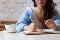 Well groomed woman hand holding gold pen and writing notes with gold pen in notebook. cup of hot butterfly pea latte or Royalty Free Stock Photo