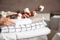 Well groomed woman hands holding the cotton branch with pile of folded bed sheets and blankets Royalty Free Stock Photo