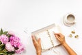 Well-groomed woman hands is writing in diary with stationery supplies set onside and peonies bouquet Royalty Free Stock Photo