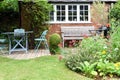 A well kept back yard or garden with lawn, flowers and seating area