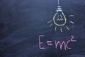 Well-known physical formula. E=mc2 on a chalk Board. Drawing of a light bulb. The concept of a sudden idea Royalty Free Stock Photo