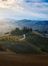 Well known Tuscany landscape with grain fields, cypress trees and houses on the hills at sunset. Summer rural landscape with Royalty Free Stock Photo