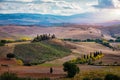 Well known Tuscany landscape with grain fields, cypress trees and houses on the hills at sunset. Summer rural landscape with Royalty Free Stock Photo