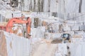 Well loader on a steep dirt road in the white marble quarries. In the background the walls with the texture of the marble and a