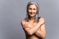 Well-looking mature woman hugging herself isolated on gray Royalty Free Stock Photo