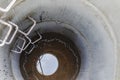 A well made of reinforced concrete rings with water at the bottom. Inside the well. Sewer well from the inside