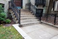 Well maintained concrete stairs to a brownstone, elegant wrought iron railing