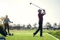 Well played. a focused young male golfer about to swing and play a shot with his golf club outside on a course. Royalty Free Stock Photo