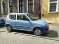 Old blue small compact car Fiat Seicento parked near old house