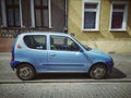 Old blue small compact car Fiat Seicento parked near old house