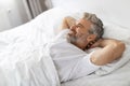 Well-rested happy middle aged man relaxing in bed Royalty Free Stock Photo