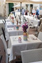 Well-served tables in a cafe restaurant, fresh colored flowers in vases, white tablecloths, summer terrace. Holidays in Italy Royalty Free Stock Photo