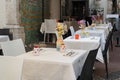 Well-served tables in a cafe restaurant, fresh colored flowers in vases, white tablecloths, summer terrace. Holidays in Italy Royalty Free Stock Photo