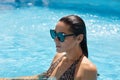 Well tanned beautiful female posing in water, wearing swimming suit and trendy sunglasses, swimming in swimming pool, enjoying Royalty Free Stock Photo
