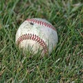A well-used softball in the grass.
