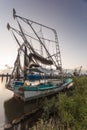 Well worn shrimping boat docked on a shore in the bayou
