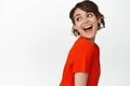 Wellbeing. Beautiful brunette woman laughing, posing coquettish, gazing behind shoulder at copy space and smiling flirty Royalty Free Stock Photo