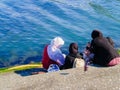 Rear view four Muslim women in hijab sitting by bay