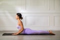 Wellness Attractive Asian woman in purple wear doing yoga Cobra pose at home to meditation comfortable and relax,Calm of healthy Royalty Free Stock Photo