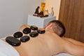 Wellness concept. Handsome young man relaxing under the stimulating effect of a traditional hot stone massage in a luxury spa and Royalty Free Stock Photo