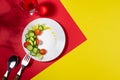 Wellness food - fresh salad of tomato, cucumber, celery on white plate in hard light with shadow with drink on red, yellow.