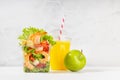 Wellness fresh take away food - set of orange juice, green apple and tropical salad with shrimps, lettuce, red bell pepper. Royalty Free Stock Photo