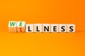 Wellness or illness symbol. Concept words Wellness and Illness on wooden cubes. Beautiful orange table orange background. Medicak Royalty Free Stock Photo