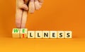 Wellness or illness symbol. Concept words Wellness and Illness on wooden cubes. Doctor hand. Beautiful orange table orange Royalty Free Stock Photo