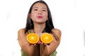 Wellness and self care - young happy and beautiful Asian Korean woman holding orange fruit sliced in half smiling cheerful in Royalty Free Stock Photo