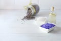 Wellness setting. Lilac sea salt, massage oil , lavender flowers on white wooden background. Royalty Free Stock Photo