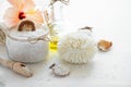 Wellness setting. Sea salt in glass, soap, towel, olive oil and flowers on white textured background.