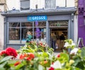 Wells, UK- August 4, 2023: Entrance to Greggs bakers with flowers in front