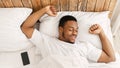 Wellslept Black Guy Awakening In Bed Stretching Hands In Bedroom Royalty Free Stock Photo