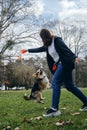 Welsh corgi pembroke dog jumps and wants toy. Female owner is smiling, enjoying the moment with her pet in park. A Royalty Free Stock Photo