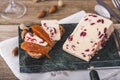 Wensleydale cheese with cranberries, red wine, honey, nuts, raisins on wooden cutting board. Black concrete background Royalty Free Stock Photo