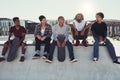 Were the coolest dudes in this town. Full length shot of a group of friends sitting together on a ramp at a skatepark.