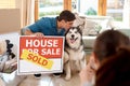 Were happy with our new home. a happy young couple and their dog taking photos with a sold sign in their new home. Royalty Free Stock Photo