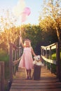 Were hitting the road leaving a trail of pink behind. a happy little girl holding balloons and a teddy bear while Royalty Free Stock Photo