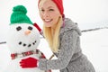 They were inseperable all winter long. a beautiful young woman building a snowman.