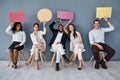We were just thinking out loud. Portrait of a group of businesspeople holding speech bubbles while sitting in line Royalty Free Stock Photo