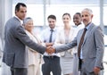 Were moving forward, together. Cropped portrait of two businessmen shaking hands in front of their colleagues. Royalty Free Stock Photo