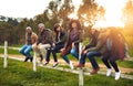 Were never bored when were together. a happy group of friends sitting in a row on a fence together. Royalty Free Stock Photo