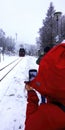 Tourist in red anorak films arrival of historical narrow gauge railroad in snowy Harz mountains with cell phone