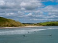 Surfers ride the waves in Clonakilty, summer. Water sports in Ireland, landscape. The Irish
