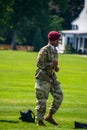 Male member of the Army Airborne Division wearing their military camouflage and a burgundy beret demonstrates a maneuver on the