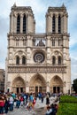 Western facade of the Notre Dame cathedral in Paris, France with crowd of tourists in front