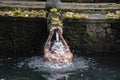 A western man bathing with sacred water according to hindu religion devotion with faith in a temple in Bali