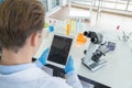 A western scientist man holding blank space tablet, working on test tube to analysis and develop vaccine of covid-19 virus in lab