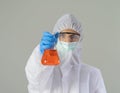A western scientist woman with Covid-19 suit and mask holding test tube to analysis vaccine of covid-19 virus in lab or laboratory